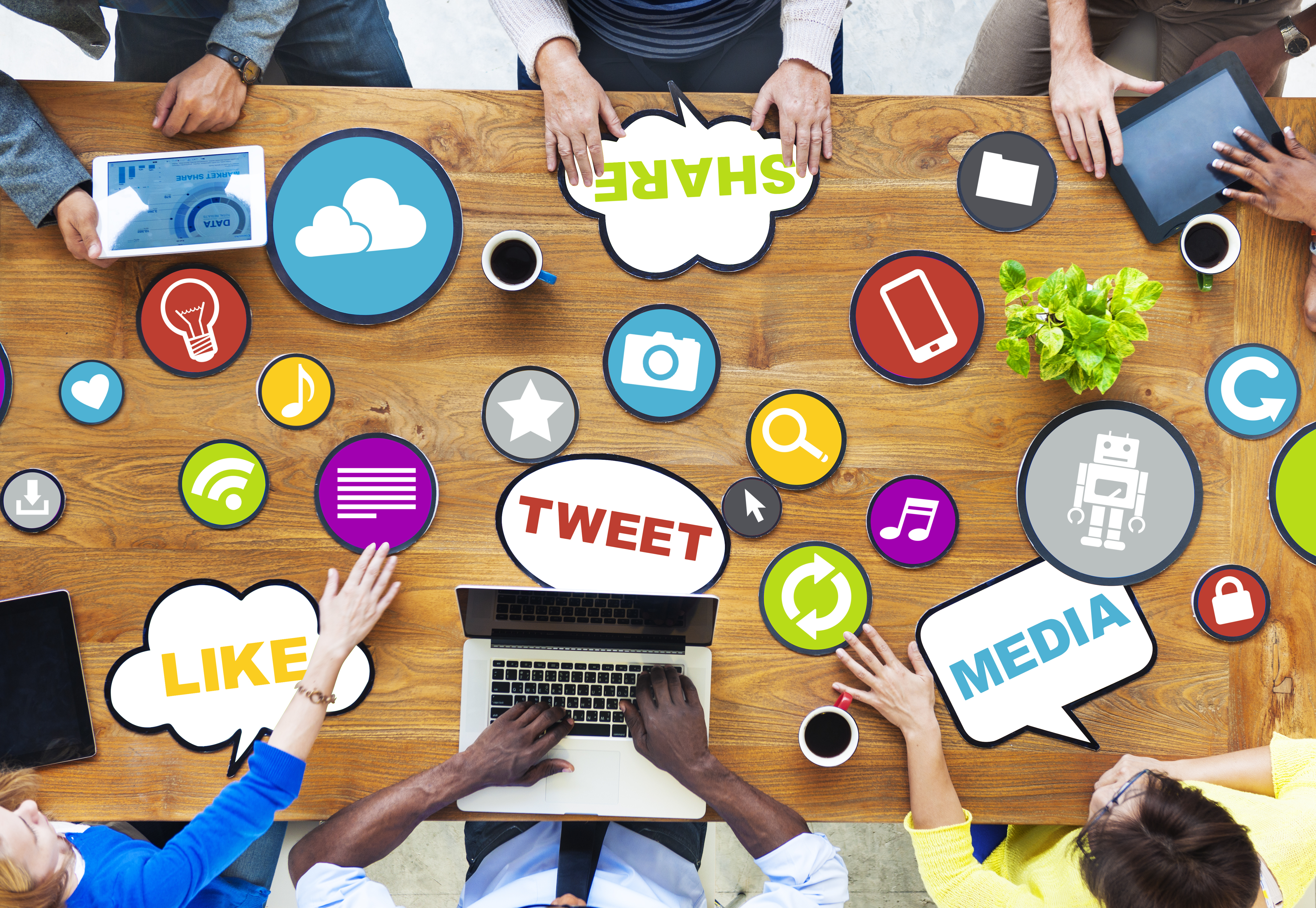 Group of people around a wooden table with speech bubbles of social media buzz-words.